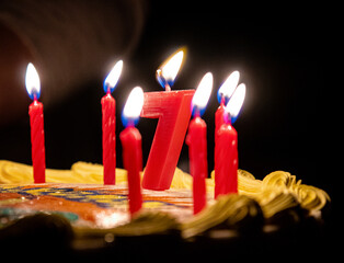 Closeup shot of burning red candles on a seven birthday cake