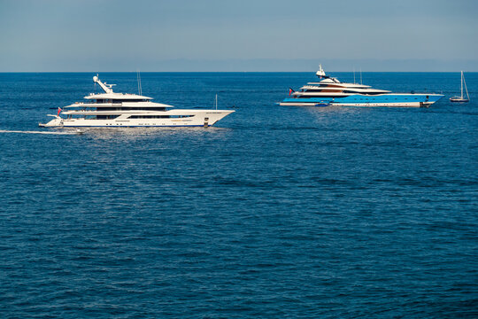 The Two Huge Mega Yachts Are Moored In Sea At Sunny Day, The Chrome Plated Handrail, Sun Reflection On Glossy Board Of The Motor Boat