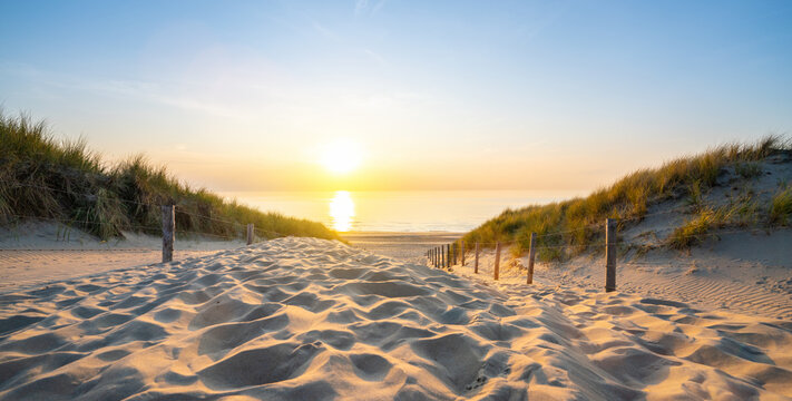 Wooden path at Baltic sea over sand dunes with ocean view, sunse