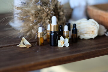 Oils in dark glass jars. Essence for skin health. Aromatic oil and dry colors on a wooden table.
