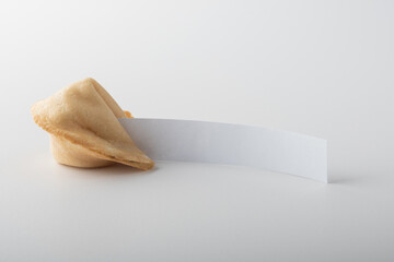 A whole traditional Chinese fortune cookie with a blank note for text, on a light background. Wish...