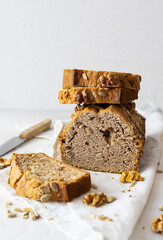 Fresh homemade bread with seeds and nuts on a light napkin. Walnuts on the table. A knife in the background. Light background