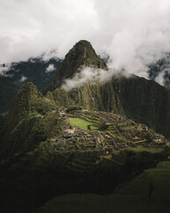 Bird's eye view of the ancient Machu Picchu citadel with a view of forested mountains and clear sky