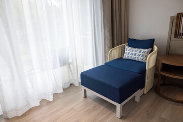 Fototapeta na wymiar Blue sofa sits in the living room by the window with white curtains of luxury cozy. minimalist concept