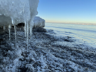 Scenic view of the icicles hanging on the frozen rocks against the seascape on a sunny day