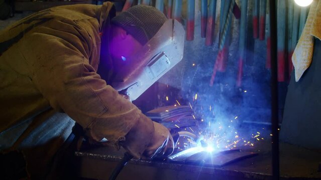 A man welds plates for body armor from springs. homemade armor plate. Factory worker welds metal. The man is welding. Welding with argon or electrode, using a welding machine. Sparks and flashes fly