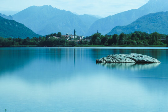 Beautiful landscape of Alserio lake against mountains and blue sky in bright sunlight in Como, Italy