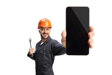 Worker with an orange helmet holding a wrench and showing a smartphone