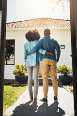 Look at our new place. Rearview shot of an unrecognizable couple holding each other while standing and looking at their new home.