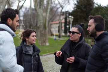 Four people talkin with each others. They are having fun, laughing at park. 