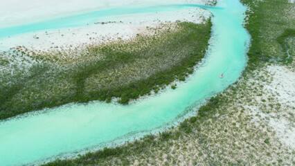 Aerial view of people sailing down a river in a white tiny boat at Exumas, Bahamas