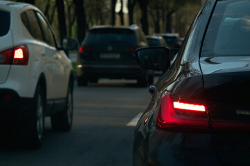 Standing in traffic and waiting. Close up view with rear red lights of the cars. Transportation industry.