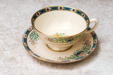 Antique tea cup and saucer on a gray table.