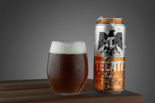 Mexico ,CDMX - April 12, 2022: Tecate Ambar with frost with ice and a glass with dark beer next to it