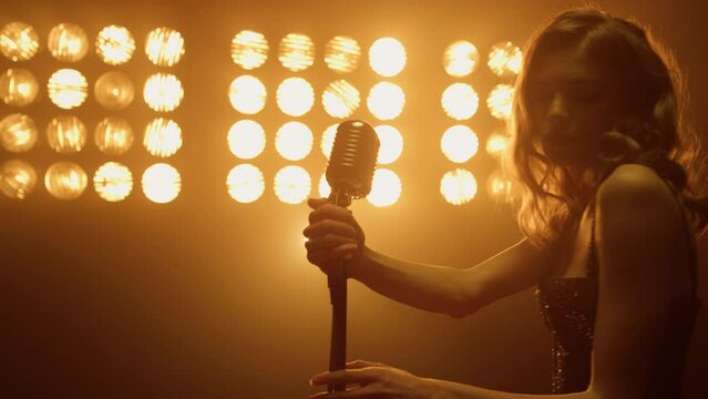 Sexy woman take microphone preparing sing solo on night club stage close up.