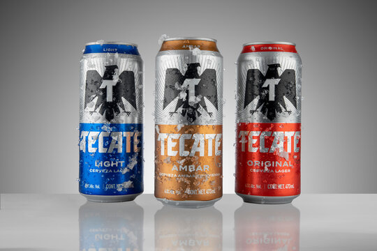 Mexico ,CDMX - April 12, 2022: Canned Tecate of three different flavors, amber, red and light, frosted with ice and white background