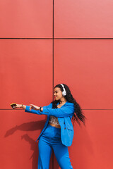 Dance student, training outdoors, wearing modern stylish blue clothes, with a red wall in the...