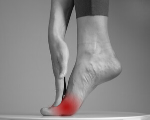 Pain in ball of foot. Woman holding leg with red spot closeup. Ache in metatarsal heads. Intense...