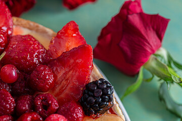 Beautiful delicious sweet cake with berries. Strawberries, kiwi, currants, blackberries, raspberry, pineapple on the biscuit. Fruit variety. Dessert. Bouquet of roses. Soft focus. Macro.Top view. 