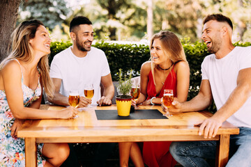 Group of young people have a good time in  backyard at a wooden table and drink beer