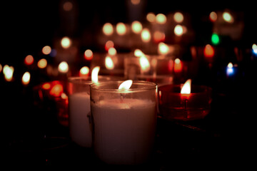 Red, white, blue, and green candles with black background and bokeh