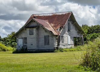 Closeup of an old abandoned house with a rusty roof under the stormy clouds