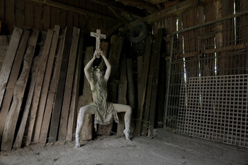 A demon like figure dressed in rags holds a crucifix up  
high in her hands. The horror figure...
