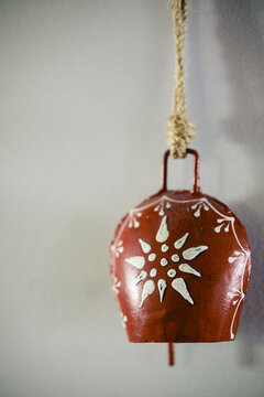 Vertical closeup shot of a painted red cowbell on a string