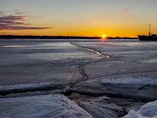 Beautiful sunset over a frozen river with ice cracks. northern landscapes
