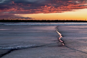 A beautiful dramatic sunset over a frozen river with cracked ice. northern landscapes