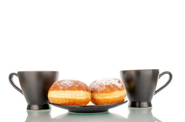 Two sweet donuts filled with jam with two black ceramic cups on a saucer, macro, isolated on a white background.