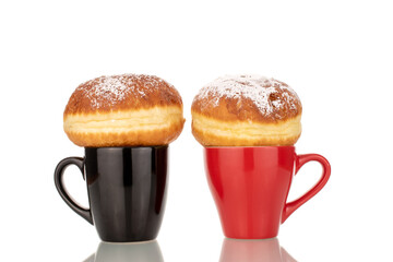 Two sweet donuts stuffed with jam with two ceramic cups, macro, isolated on a white background.