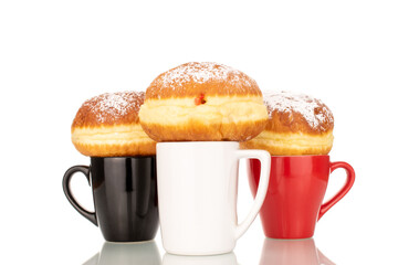 Three sweet donuts stuffed with jam with three ceramic cups, macro, isolated on a white background.