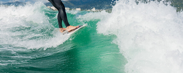 Wakeboarding. Close up of woman in wetsuit learning to wakesurfing behind wakeboard boat. Female surfing motorboat waves on river. Banner image with copy space