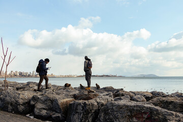 Two man on rocks by sea. They are watching beautiful sky and sea view. 