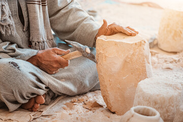 A worker or craftsman works with a pickaxe hammer to process stone