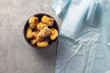 Ready-made homemade nuggets in a brown clay bowl on a blue napkin background