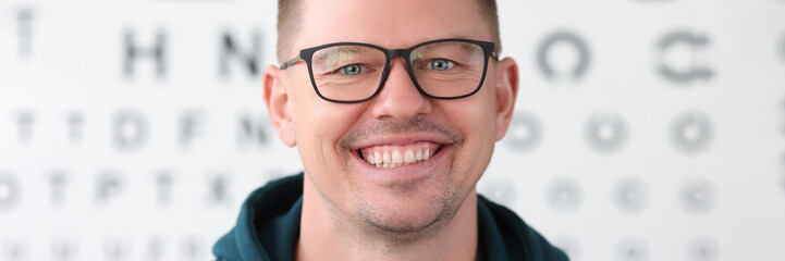 Obraz premium Portrait of smiling man with glasses on background of table for vision test