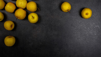 Yellow sweet ripe apples are scattered on the black table