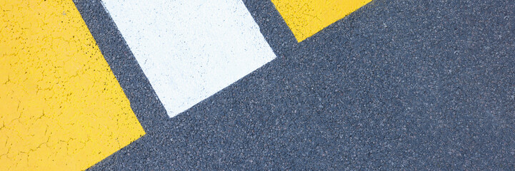 Fototapeta premium Closeup of yellow and white stripes on gray asphalt background