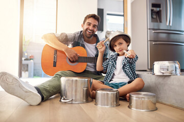 Are you ready for an encore. Portrait of a happy father accompanying his young son on the guitar while he drums on a set of cooking pots.