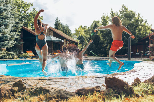A young group of people jumping into the swimming pool.Having fun and refreshing on a hot summer day.	
