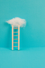 Ladder with a cloud on top, blue colored background, copy space, dreaming of success, creative and...