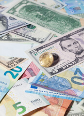 A gold-colored coin with a denomination of 10 Russian rubles lies on top of USA and European paper money of different denominations - USD, EUR. View from above. Russian ruble coins.