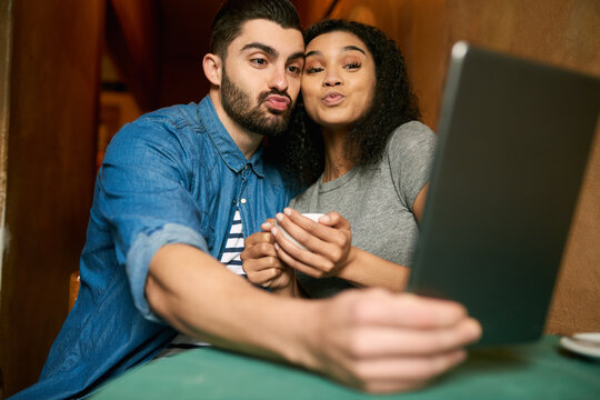 Hes becoming more like me, fun. Cropped shot of a young couple taking a selfie in a cafe.
