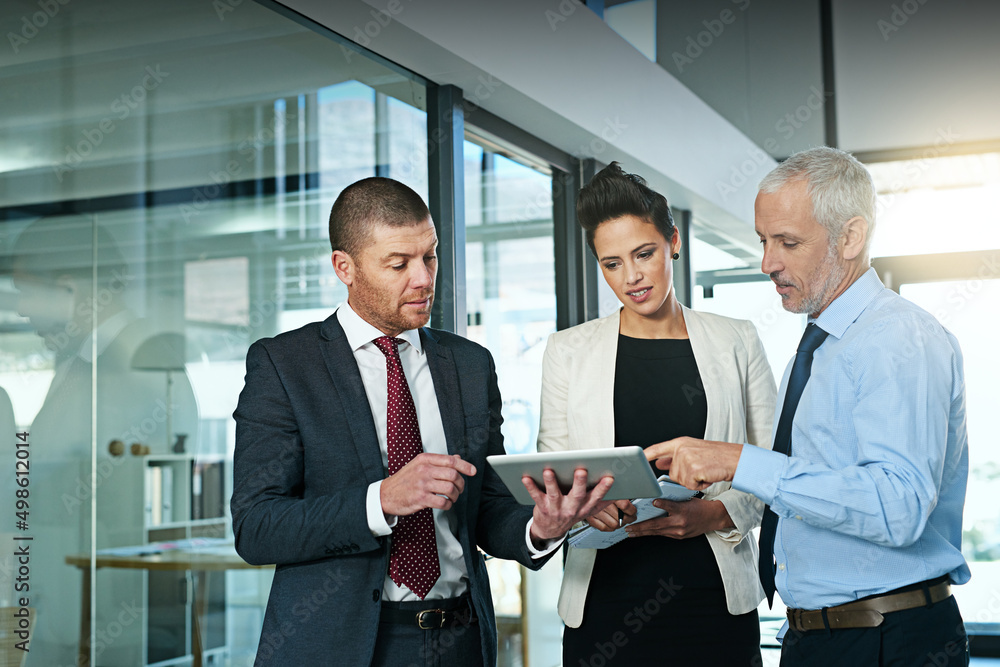 Leinwandbilder Using technology to boost their brainstorming sessions. Shot of a business team using a digital tablet while having an informal meeting.