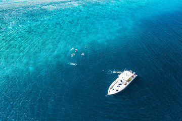 Naklejka premium Beautiful turquoise ocean water and boat, view aerial drone seascape. Tropical sea waves, amazing aerial coral reef, lagoon. People recreational outdoor activity, swimming, snorkeling, diving tourism