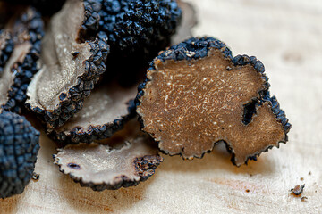 Soft focus of truffles.Thinly sliced mushrooms. Black raw champignons on a beige burlap. Top view. Dark background. Shallow depth of field.The artistic intend and the filters.