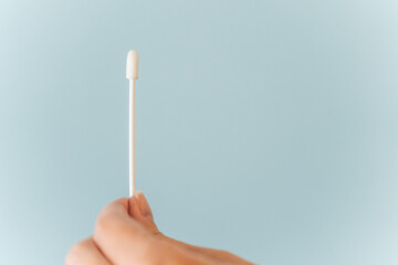 Hand holds Covid-19 PCR nasal swab against background with copy space