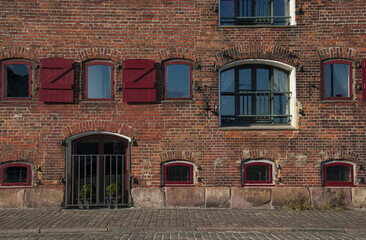 Old red brick building with arched windows and maroon red shutters in Copenhagen - Powered by Adobe